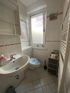 ein Bad mit einem Waschbecken, einem WC und einem Fenster in der Unterkunft Blue Chili 17 Schöne 3 Zi Toplage Boxspringbett Balkon Wifi in Magdeburg