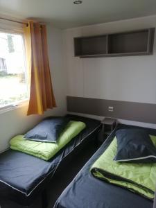 two beds in a room with a window at SAS MHVACANCES LOUE MOBILHOME 2 CHAMBRES PROCHE CHATEAUX et ZOO BEAUVAL in Onzain