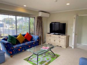 a living room with a blue couch and a tv at Paradise Hideaway in Rotorua