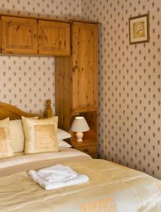 a bedroom with a bed with a wooden headboard and a lamp at Tor Dean Guest House in Torquay