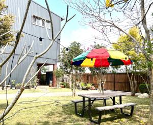 新社區的住宿－新社小宿食光包棟民宿，一张带五颜六色的雨伞和长凳的野餐桌