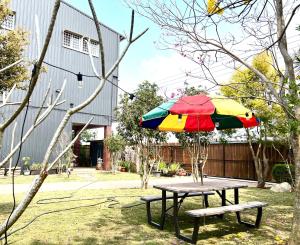 新社新社小宿食光包栋民宿的一张带五颜六色的雨伞和长凳的野餐桌 更多17张照片
