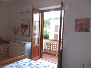 een slaapkamer met een deur naar een balkon bij Villetta Fiorita in San Vito lo Capo