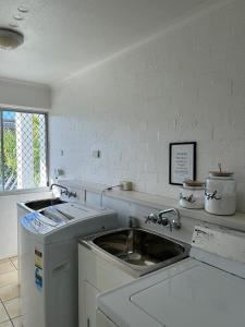 a white kitchen with a sink and a counter at Noosa Parade Holiday Inn in Noosa Heads