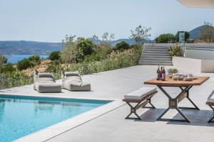 un patio avec une table et des chaises à côté d'une piscine dans l'établissement Oikos Boutique Residences Private Estate, à Plateies