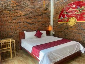 a bedroom with a bed with a brick wall at Sunshine villa thuy bieu in Hue