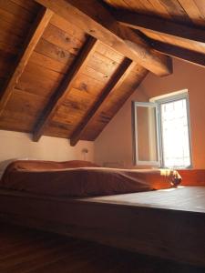 a bed in a room with wooden ceilings and a window at Casa Olivia Lacremà in Finale Ligure