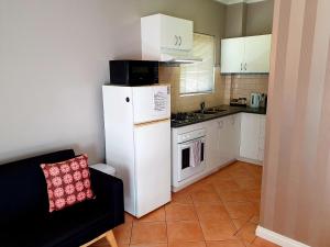 a small kitchen with a white refrigerator and a stove at M2 West Perth Studio Apartment near Kings Park in Perth