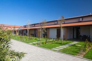 un bâtiment avec une cour plantée d'arbres et d'herbe dans l'établissement Delfino Tuscany Resort, à Marina di Cecina