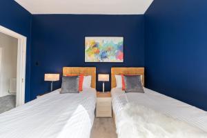 two beds in a room with blue walls at Stylish Luxury Large 4BR KingBed in Barrow in Furness