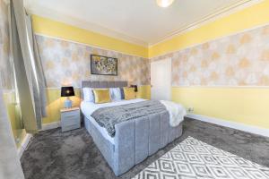 1 dormitorio con cama y pared amarilla en Stylish Luxury Large 4BR KingBed, en Barrow-in-Furness