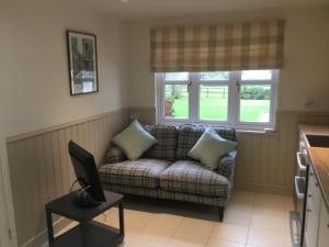 ein Wohnzimmer mit einem Sofa und einem Laptop auf dem Tisch in der Unterkunft Cute Cottage 2024 Traveller Award in Yateley