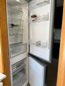 um frigorífico aberto com a sua porta aberta e as suas prateleiras em Appartement standing 58m plage à 3mn en voiture em Roses