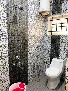 y baño con aseo y azulejos blancos y negros. en Kalyani Homestay en Kodaikānāl