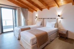 two beds in a room with a large window at Sofita με θέα τη θάλασσα Villa Athina in Preveza