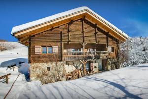 a log cabin with a balcony in the snow at Chalet OVO La Vieille Ferme - OVO Network in Manigod