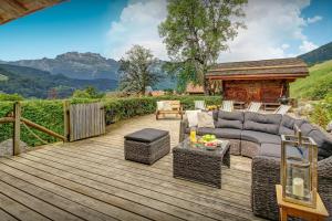 a wooden deck with a couch and chairs on it at Chalet OVO La Vieille Ferme - OVO Network in Manigod