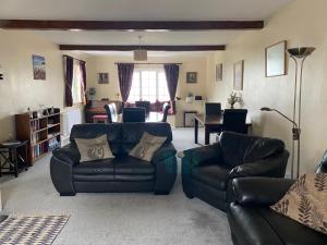 a living room with two leather couches and a table at Spacious family & dog friendly home from home with sea views and private garden in Porlock