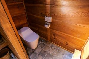 een kleine badkamer met een toilet en houten wanden bij 古民家オーベルジュmocca in Kokuryō
