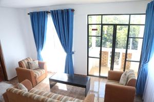 a living room with blue curtains and a couch and a table at Span Grand @ Nuwara Eliya in Nuwara Eliya