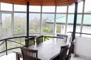 una mesa y sillas en una habitación con ventanas en Span Grand @ Nuwara Eliya, en Nuwara Eliya