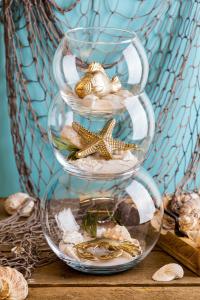 a three tiered glass shelf with shells and starfish at Ferienwohnung mit Terrasse - Insel Usedom in Trassenheide
