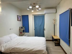 a bedroom with a white bed and a blue window at 鰆居Chun House 三仙台 in Chenggong