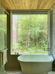 a bathroom with a large window and a bath tub at KOMOREBI House -北軽井沢 木漏れ日の家- ペット可 in Kita-karuizawa