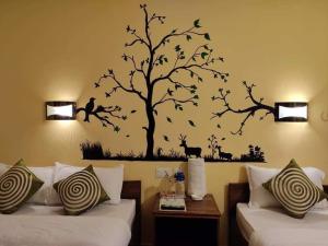 Hotel Mirage Sauraha في سوراها: غرفة بسريرين وشجرة فيها طيور