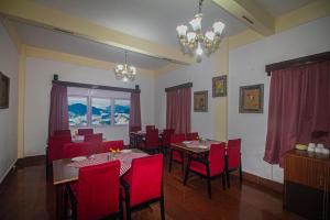 a dining room with red chairs and a table at Central Gleneagles Heritage Resort Former Bungalow of Ex-TATA Chairman Russi Mody The Mall Road Darjeeling in Darjeeling