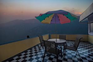 a table and chairs with an umbrella on a balcony at Central Gleneagles Heritage Resort Former Bungalow of Ex-TATA Chairman Russi Mody The Mall Road Darjeeling in Darjeeling