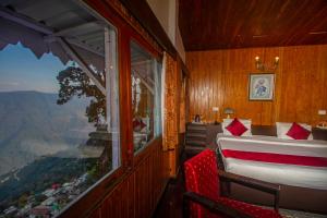 a bedroom with a bed and a large window at Central Gleneagles Heritage Resort Former Bungalow of Ex-TATA Chairman Russi Mody The Mall Road Darjeeling in Darjeeling