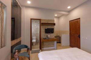 a bedroom with a bed and a desk and a television at Kailasham Stay in Dharamshala
