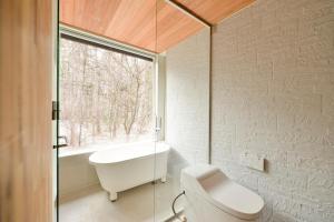 ein Bad mit einer Badewanne, einem WC und einem Fenster in der Unterkunft KOMOREBI House -北軽井沢 木漏れ日の家- ペット可 in Kita-karuizawa