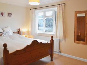 a bedroom with a wooden bed and a window at West View in Sturminster Marshall