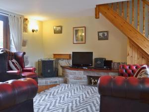 a living room with couches and a television and a fireplace at Swallows Loft in Cromford
