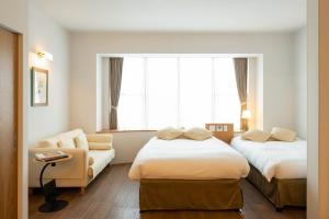 um quarto de hotel com duas camas e uma cadeira em Resort Hotel Moana Coast em Naruto