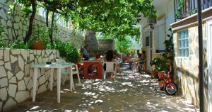 a group of people sitting at tables in a courtyard at Pansion panorama family apartment in Skala Marion