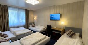 a hotel room with three beds and a tv on the wall at Hotel Austria in Gablitz