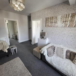 a living room with a couch and a brick wall at Willesden, Flat 2, A 1 Bedroom flat right in the heart of Llandudno in Llandudno