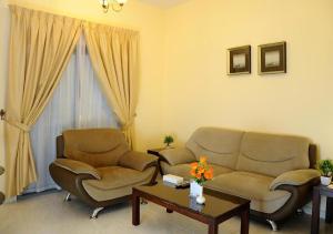 a living room with two chairs and a couch and a table at New Royal Palace Hotel Apartments in Ajman 