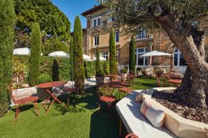 un patio esterno con tavoli, sedie e un albero di Hôtel Particulier Château Beaupin by Territoria a Marsiglia