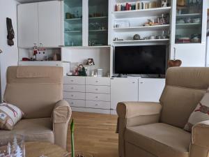 ein Wohnzimmer mit 2 Stühlen und einem Flachbild-TV in der Unterkunft Apartment Humagne - Crans-Montana Center in Crans-Montana