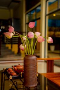un jarrón lleno de flores rosas sentado en una mesa en Hoi An Heart hostel Villa, en Hoi An