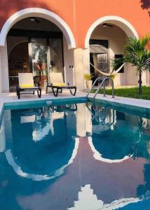 a swimming pool with two chairs next to a building at Casa Valentina: lovely house in downtown Merida in Mérida