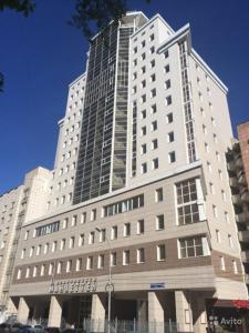 un gran edificio blanco con un cartel. en Manhattan Apartments, en Perm