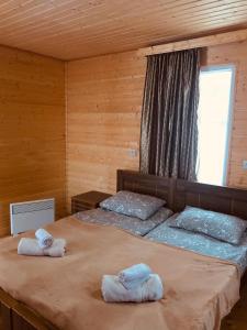 twee bedden in een houten kamer met handdoeken erop bij Ushba Cottages in Mazeri