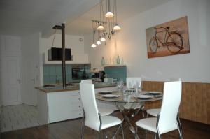a kitchen with a table with white chairs and a bike on the wall at L'Appel de la Loire in Saumur