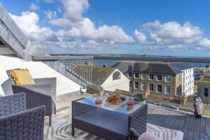 a patio with a table and chairs on a balcony at Stunning Views Over Mounts Bay with Balcony in Penzance