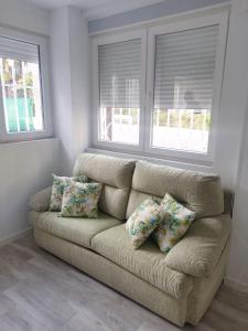 a couch in a living room with two windows at APARTAMENTO BAJO ALCOBENDAS in Alcobendas